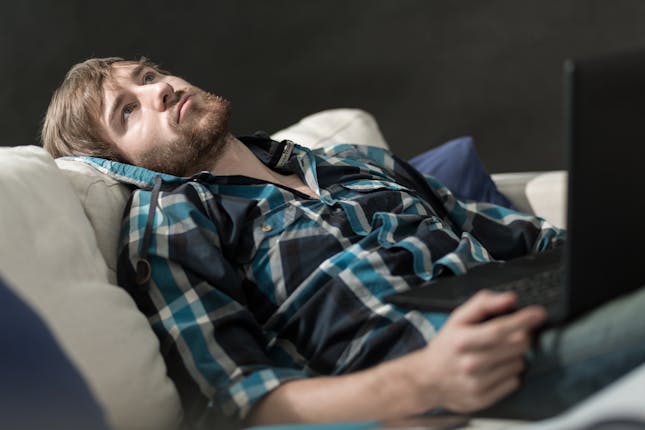 Young man in need of coping skills for depression sitting on couch staring at the ceiling.