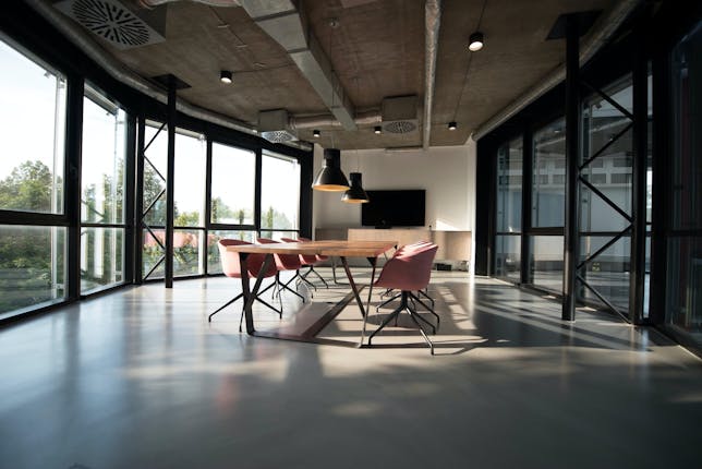 A boardroom desk with pink chairs to symbolize the necessity of a ‘seat at the table’ for women in the workplace