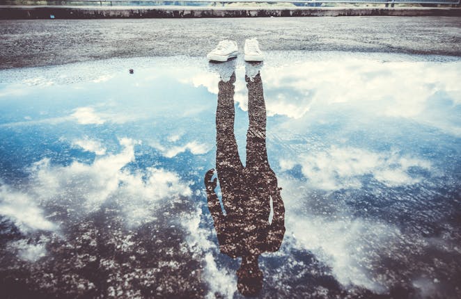 Reflection of man standing near puddle.