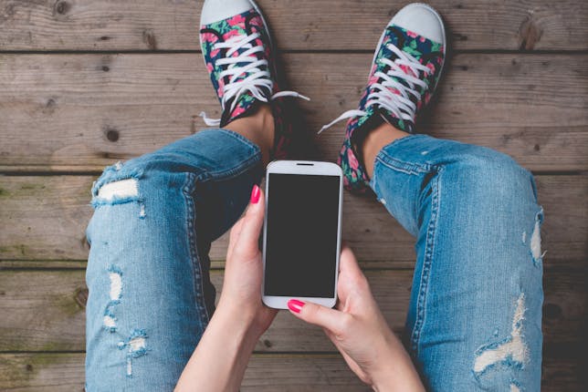 An image of a young girl on a phone showing the question all parents face, when and how do I give my kid a phone?