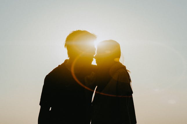 Silhouette of a couple standing close with sun rays encircling them to represent the intimacy discussed in this article