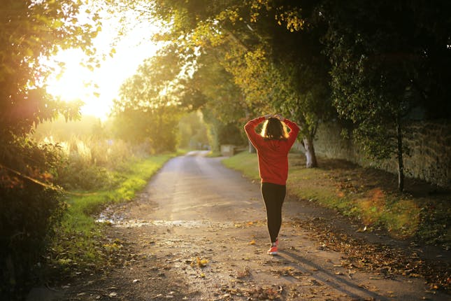 A woman slowing down to finally pause her run and take a break.